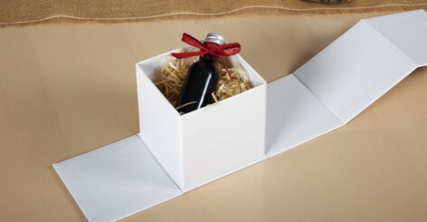 Darstellung der Geschenkbox mit Fenster im geschlossenen Zustand mit Geschenkbeispiel, einer kleinen Weinflasche und Pesto im Glas.
